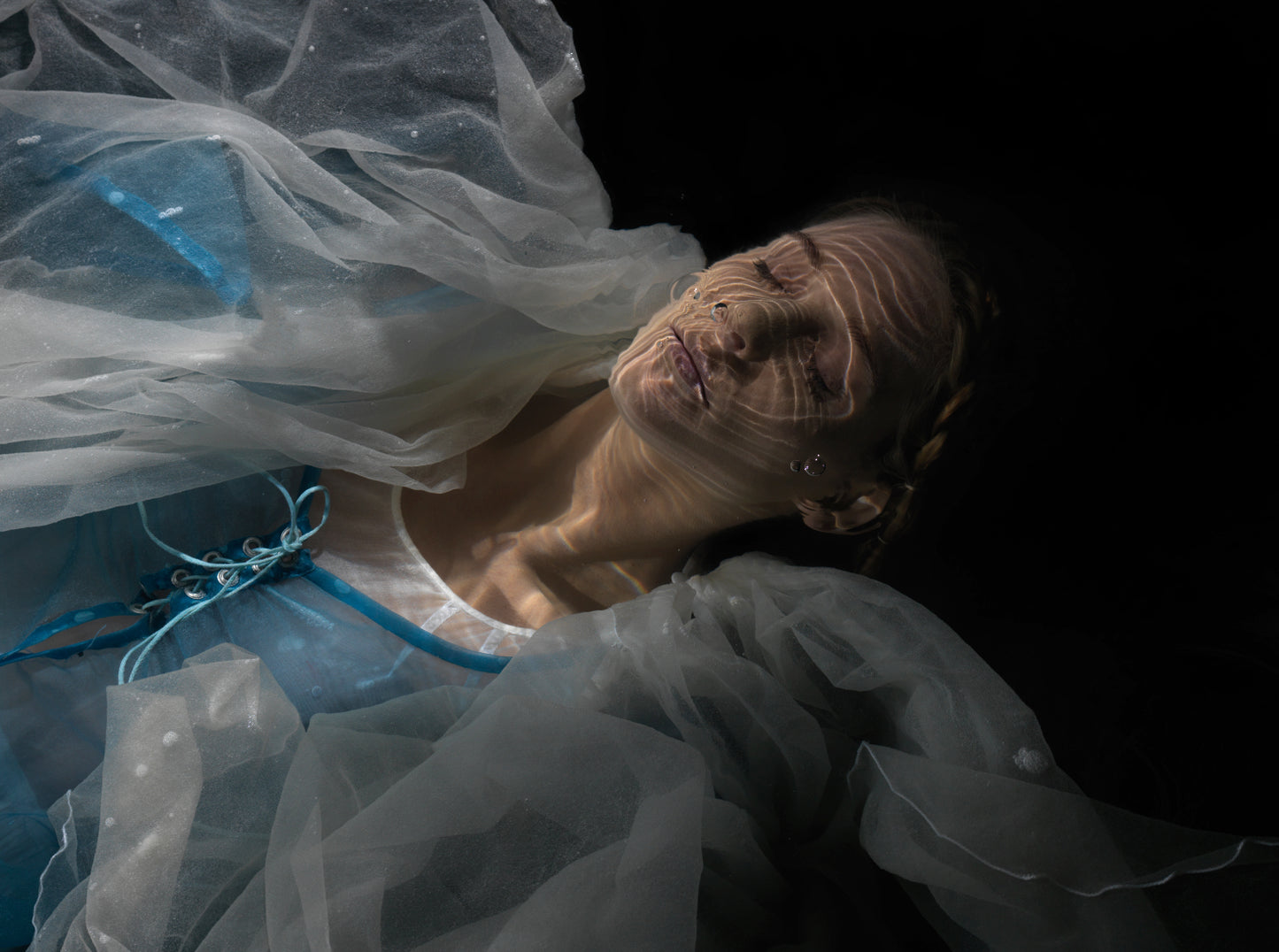 Unique archival pigment print of a woman with tulle fabric and intricate facial details, dark background.