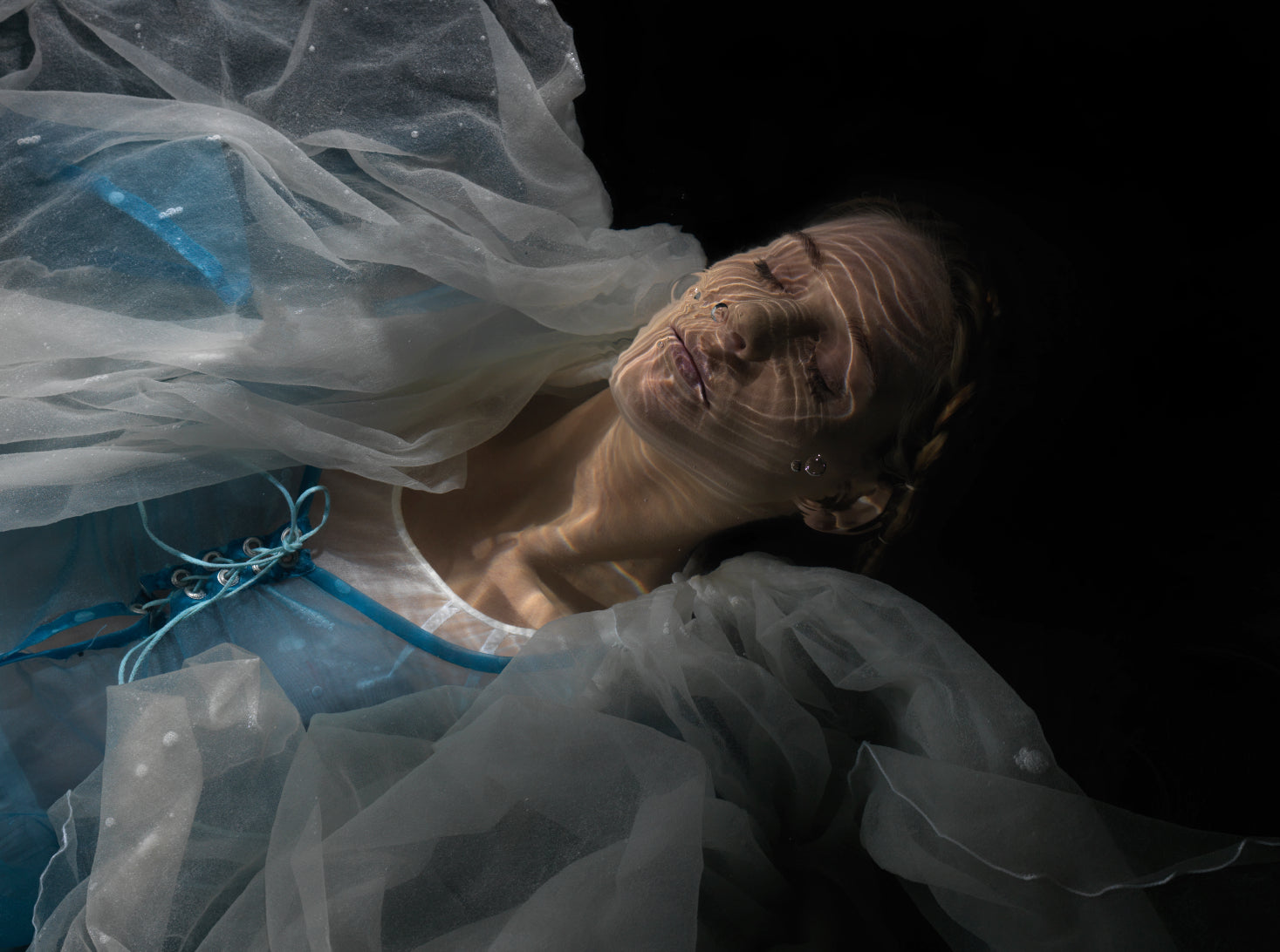 Unique archival pigment print of a woman with tulle fabric and intricate facial details, dark background.