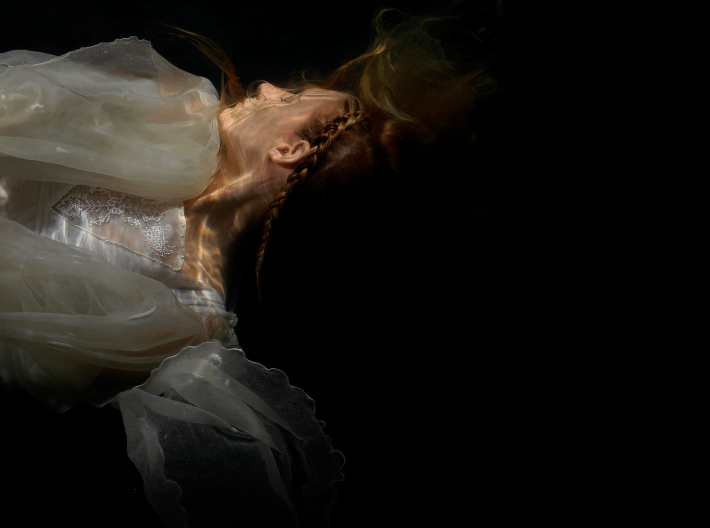 Unique archival pigment print showing a softly lit figure in flowing white fabric against black background.