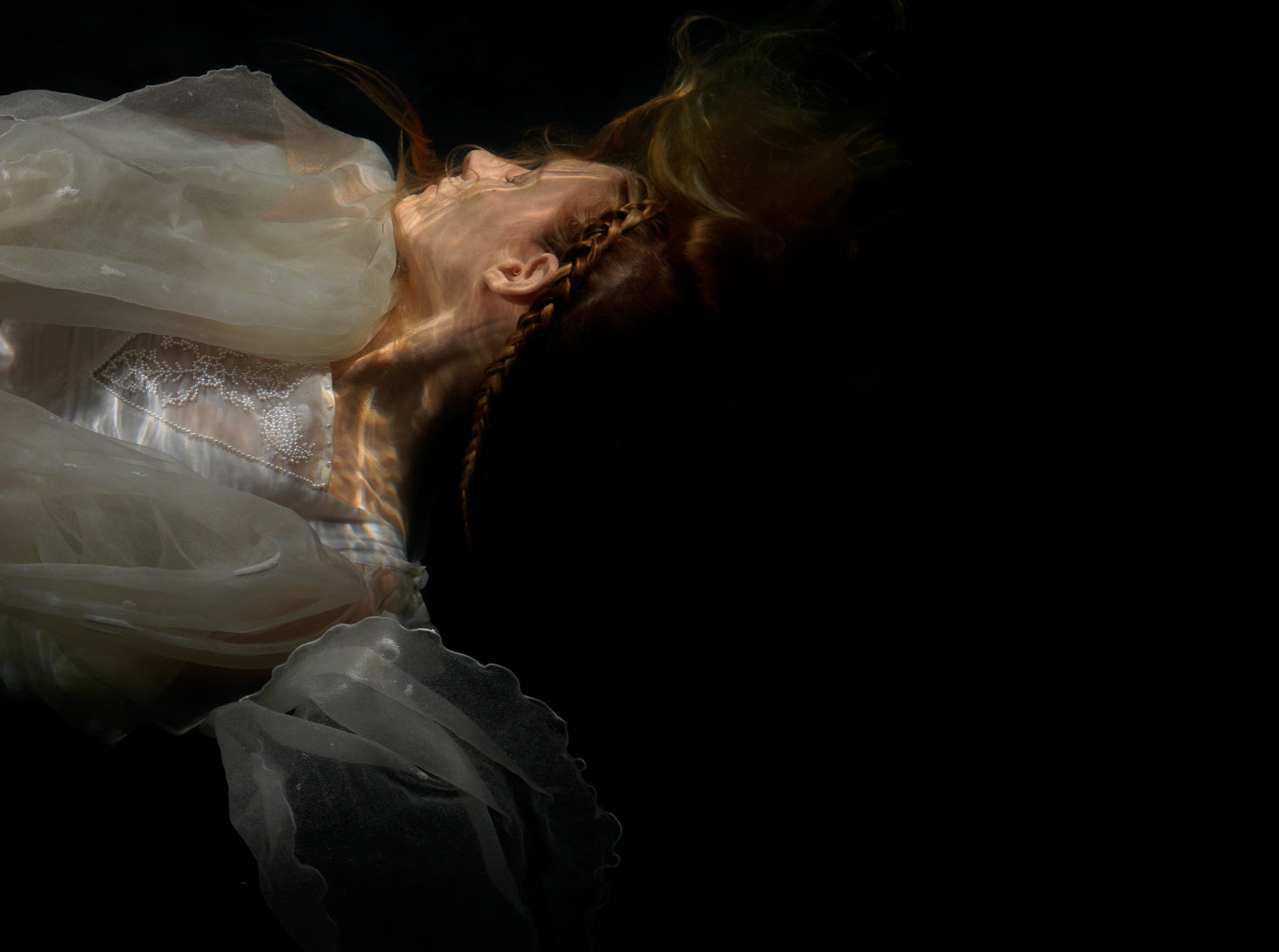 Unique archival pigment print showing a softly lit figure in flowing white fabric against black background.