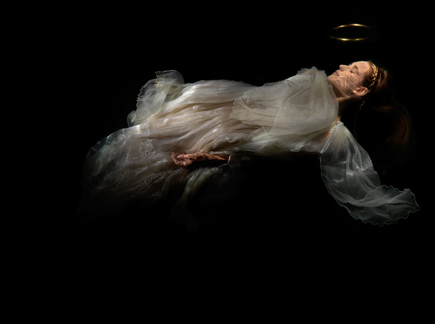 Unique archival pigment print of a woman in flowing white fabric with a golden halo on black background.
