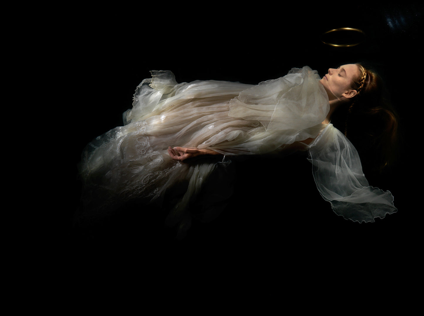 Unique archival pigment print of a woman floating in a sheer, textured white gown against a dark background.